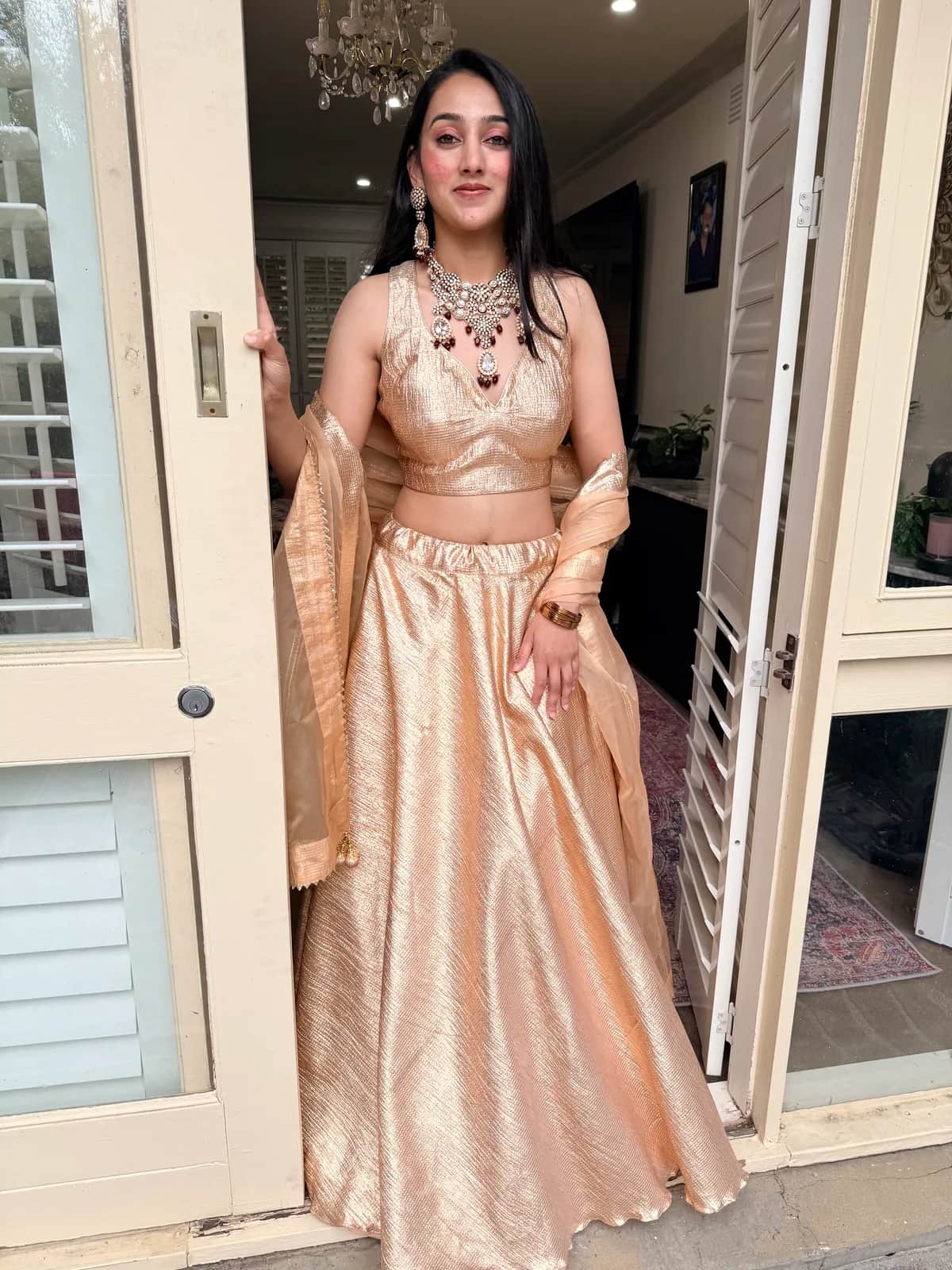 Shimmery gold lehenga with organza dupatta front view on model